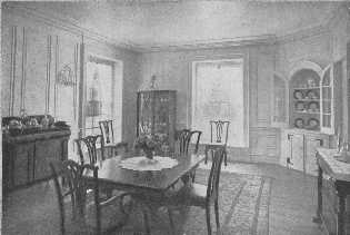 A built-in corner cupboard has an architecturally
decorative value for it supplies a spot of color in the paneled walls.
The modern china closet is bad, and the chairs have the failing of many
reproductions, the backs are a little too high for the width.