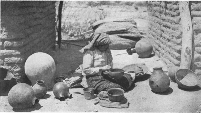 In the bright Arizona sunshine before their little square
adobe houses Indian women are fashioning pottery into curious shapes