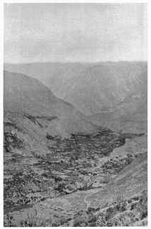 Fig. 29&mdash;Cotahuasi on the floor of the Cotahuasi canyon.
The even skyline of the background is on a rather even-topped lava
plateau. The terrace on the left of the town is formed on limestone,
which is overlain by lava flows. A thick deposit of terraced alluvium
may be seen on the valley floor, and it is on one of the lower terraces
that the city of Cotahuasi stands. The higher terraces are in many cases
too dry for cultivation. The canyon is nearly 7,000 feet (2,130 m.) deep
and has been cut through one hundred principal lava flows.